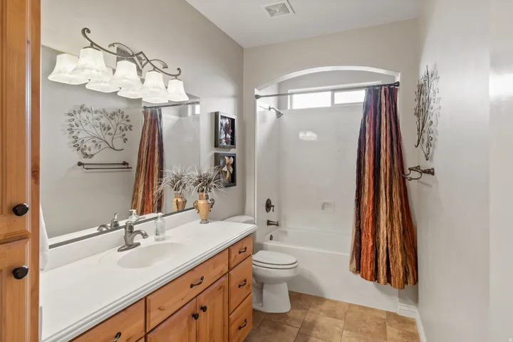 Bathroom featuring a single vanity with wood cabinetry, a white countertop, and a large mirror