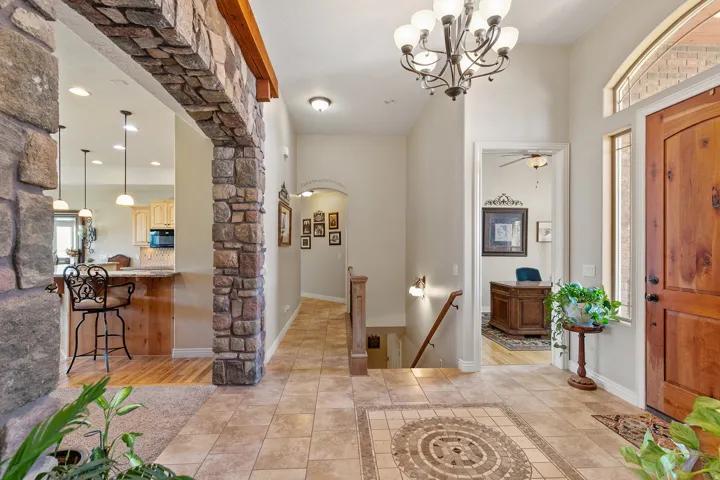 Entryway featuring tile flooring with an inlaid mosaic design, a wooden door with an arched transom window, and a stone-clad archway