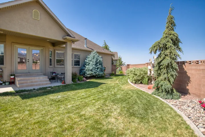 Expansive backyard featuring a stucco exterior, covered patio, double glass doors, and a decorative block privacy wall