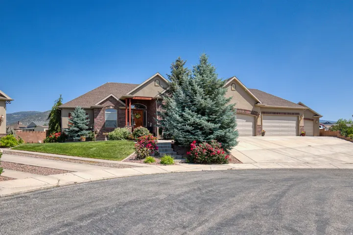 Stucco and brick exterior with a multi-car garage, mature landscaping, and an inviting entryway