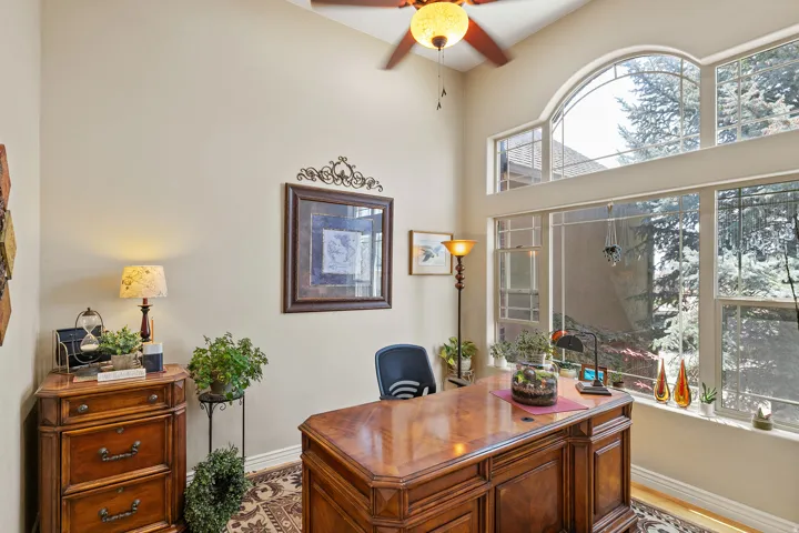 Vaulted ceiling with an integrated ceiling fan, large arched window, tall windows, and light-toned wall finishes