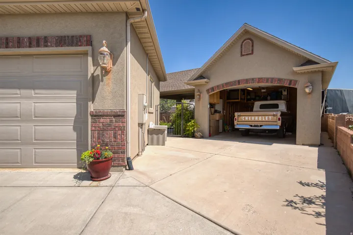 Attached garage with a panel door, textured stucco exterior, and brick detailing