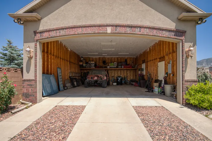 Two-car garage with overhead lighting, exposed wood-finish walls, and built-in shelving