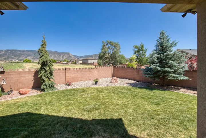 Grassed backyard with a block wall perimeter and gravel landscaping