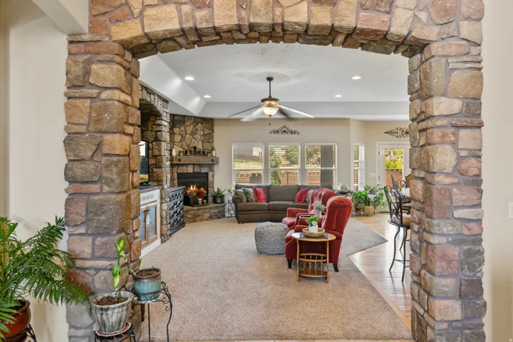 Stone archway leading to a living area with a stone fireplace, recessed lighting, and a ceiling fan
