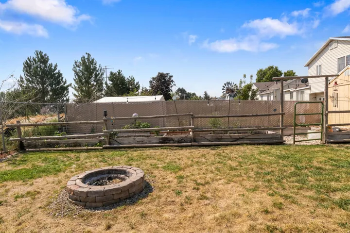 Stone-built fire pit, fenced garden beds, and a metal gate