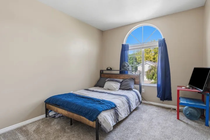 Arched window with grilles, neutral wall paint, and textured carpet