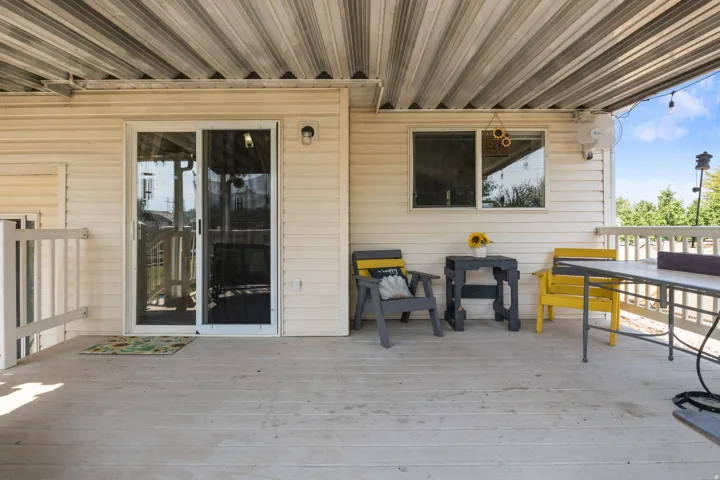 Covered outdoor deck with white siding, white railings, and a sliding glass door
