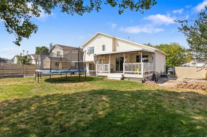 Expansive backyard featuring a covered patio, a spacious deck, and a defined gravel area with block retaining walls