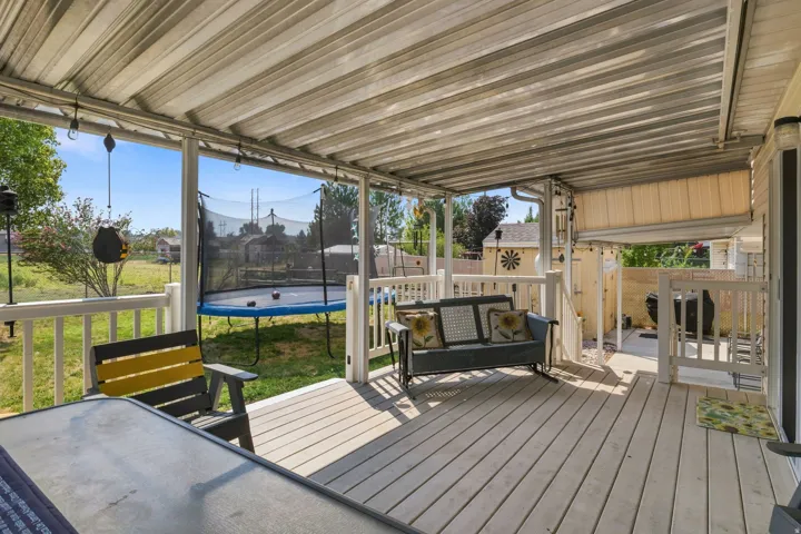Expansive covered deck with white railing, wood-finish decking, and open yard space