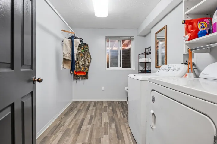 Laundry area featuring wood-finish flooring, a window, and built-in shelving