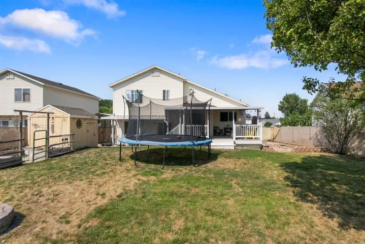Expansive backyard featuring a covered patio, white railing deck, and a raised garden bed
