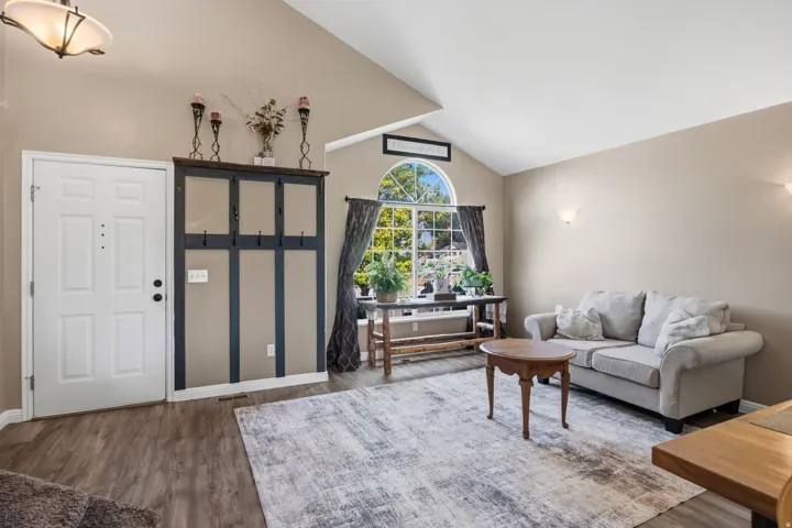 Vaulted ceiling, wood-finish flooring, half-round window, ceiling-mounted light fixture, wall sconces