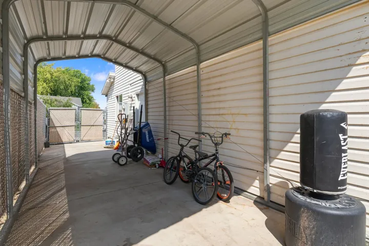 Covered carport structure with a concrete pad and chain-link fencing