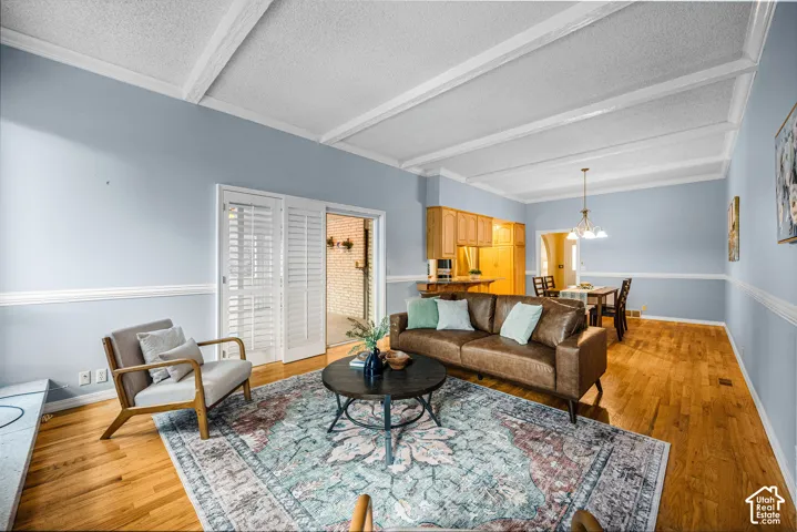 Hardwood flooring, crown molding, chair rail molding, built-in cabinetry, and white ceiling beams
