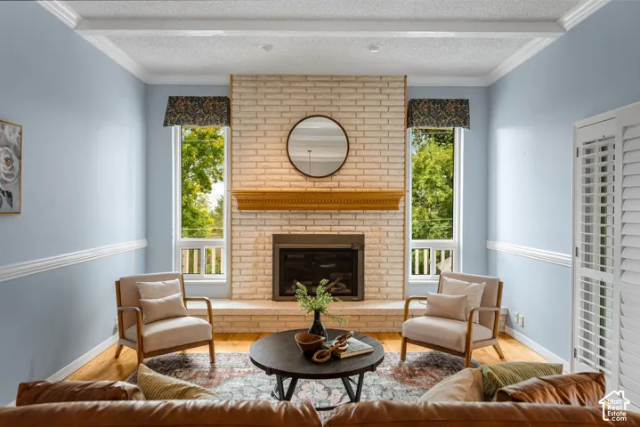 Brick fireplace with a wood-finish mantel, flanked by tall windows, crown molding, and wood-finish flooring