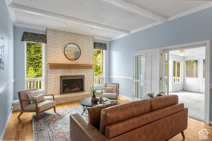 Living area featuring wood-finish flooring, a brick fireplace with a wood mantel, and large windows