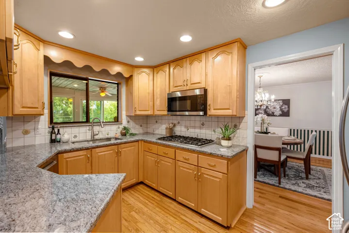 Kitchen featuring wood cabinetry, light-toned countertops, a stainless steel microwave, a gas cooktop, and recessed lighting