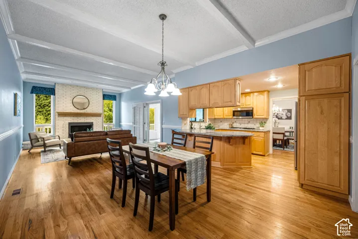 Hardwood flooring throughout, coffered ceiling, brick fireplace with wood mantel, ample kitchen cabinetry, and kitchen island with countertop seating