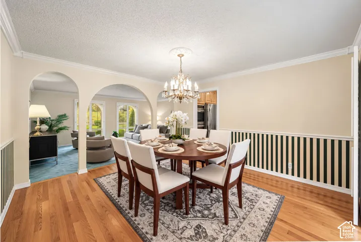 Formal Dining Room with archways, crown molding, chair rail, hardwood floors, and plantation shutters