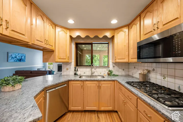 Kitchen featuring wood cabinetry, light-toned countertops, a stainless steel microwave, a built-in gas range, and a tiled backsplash