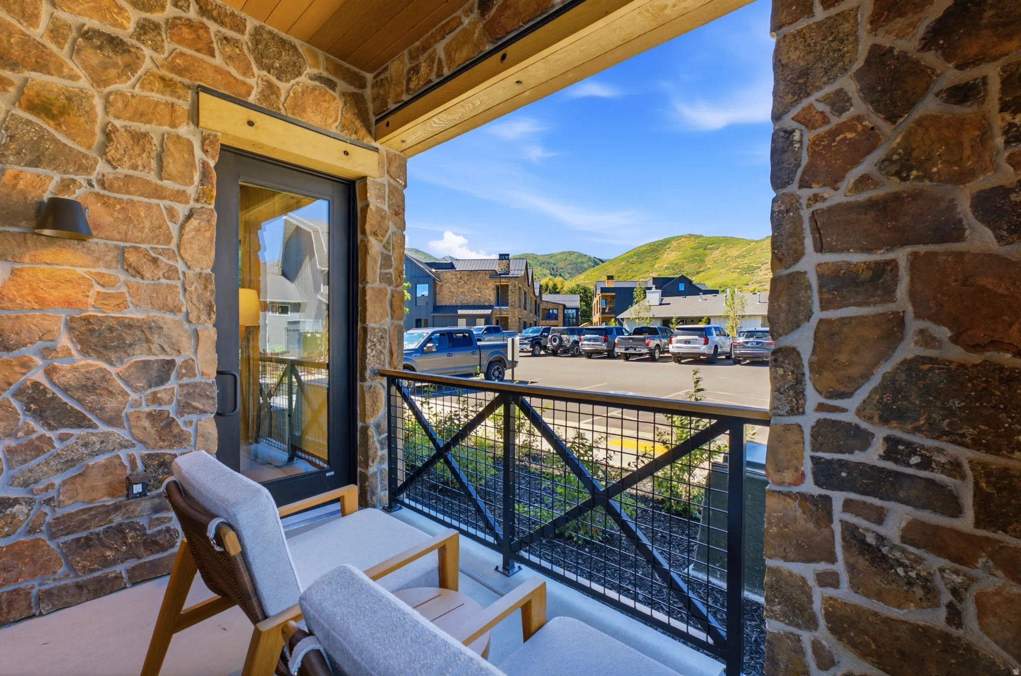 Balcony featuring stone-clad walls, wood-paneled ceiling, and a black metal railing