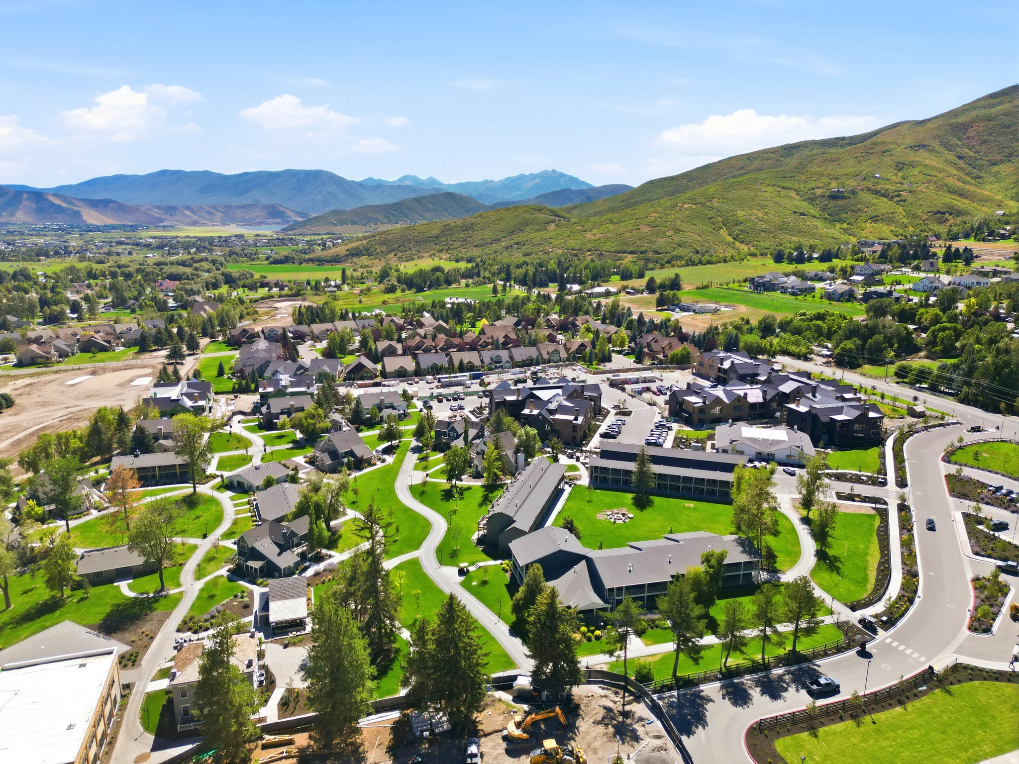 Expansive community with varied architectural styles, extensive green spaces, mature landscaping, paved pathways, and mountain scenery