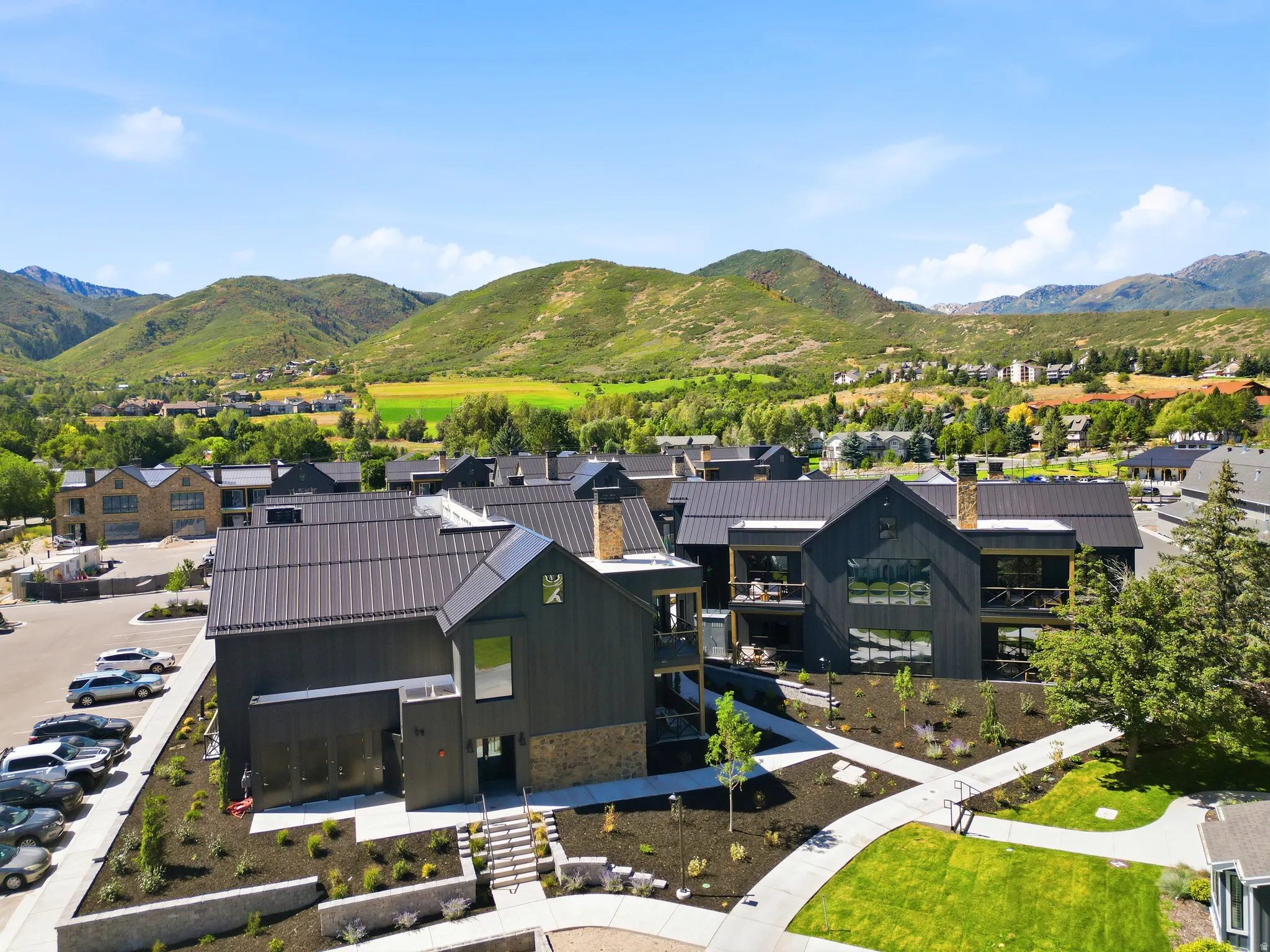 Modern residential complex featuring dark-toned vertical siding, metal roofing, stone accents, and private balconies