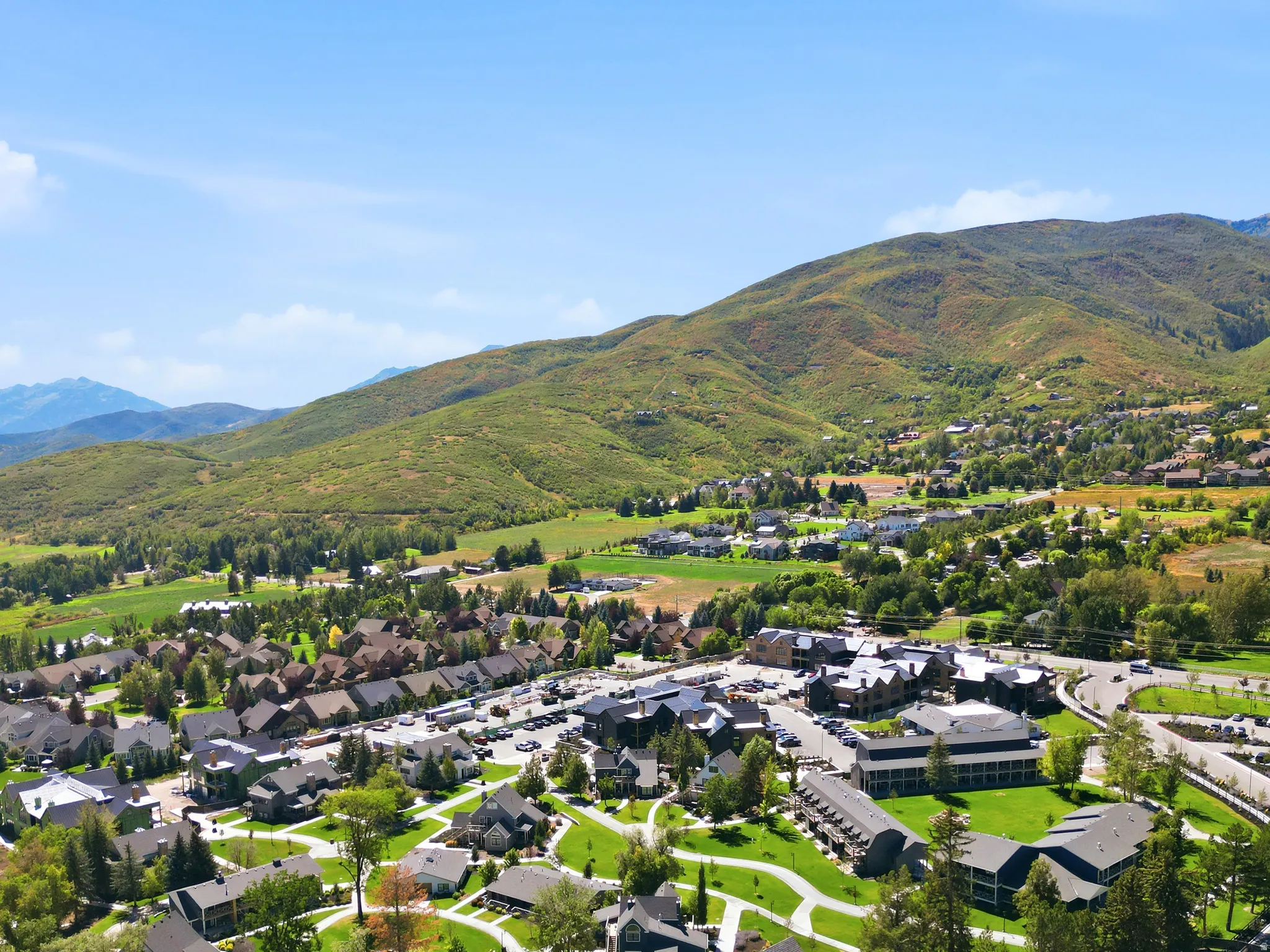Expansive mountainous scenery surrounding a community with residential properties, commercial structures, and green spaces