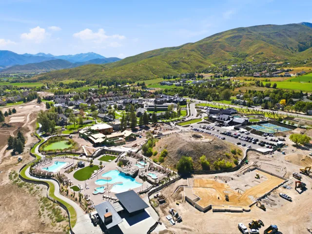 Expansive community with multiple outdoor pools, tennis courts, and a central village area, all set against a mountainous backdrop