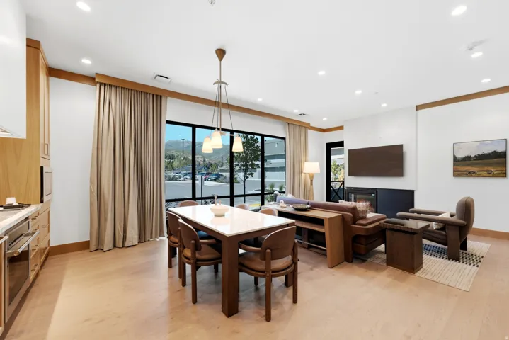 Open-concept living space featuring wood-finish flooring, recessed lighting, a modern built-in fireplace, and expansive windows