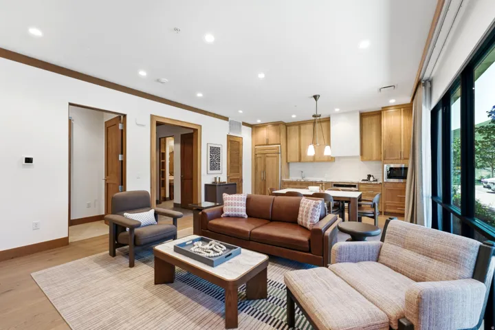 Open-concept living space with wood-finish flooring, recessed lighting, a modern kitchen with built-in appliances, and expansive windows