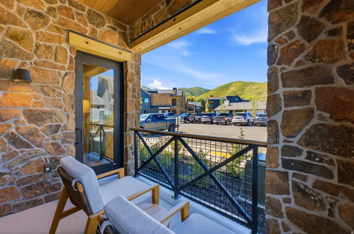Balcony featuring stone-clad walls, wood-paneled ceiling, and a black metal railing