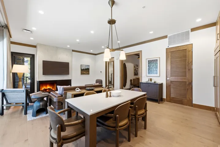 Open-concept living space with wood-finish flooring, a contemporary fireplace, recessed lighting, and a pendant light fixture