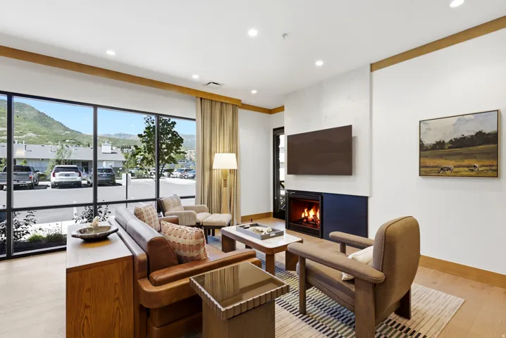 Expansive window wall with mountain backdrop, integrated fireplace, wood-finish flooring, recessed lighting, and wall-mounted television