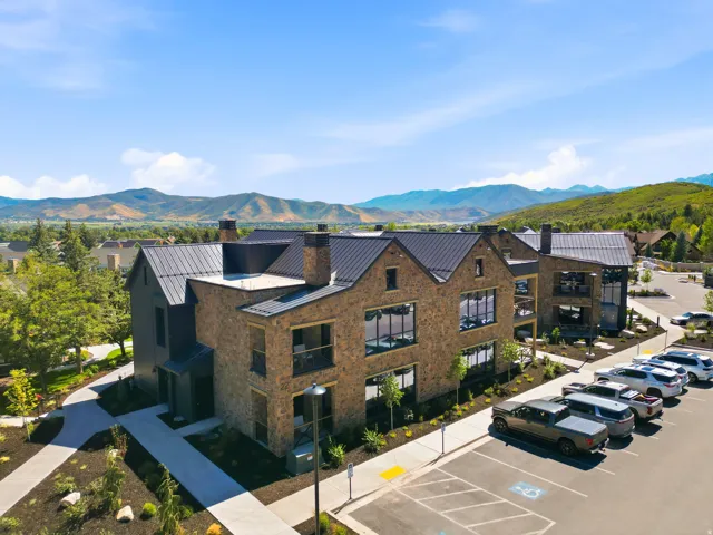 Stone and vertical siding exterior with a metal roof, featuring multiple balconies and a dedicated parking area