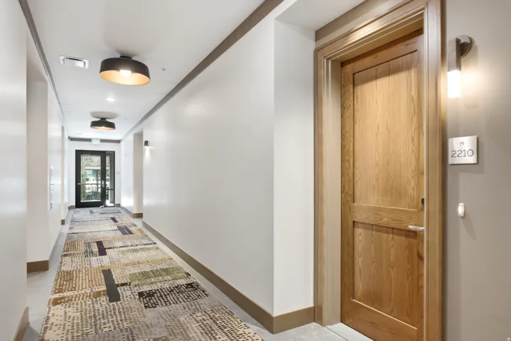 Corridor featuring patterned carpeting, recessed lighting, and modern wall sconces