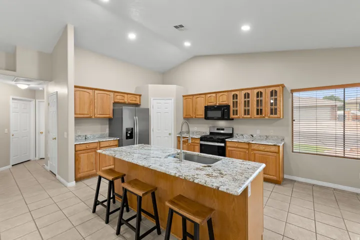 Kitchen featuring a central island with a double basin sink, light-toned cabinetry, light countertops, and stainless steel appliances