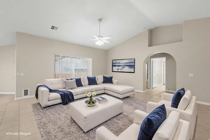 Vaulted ceilings, a wide window with vertical blinds, a ceiling fan with light, and an arched doorway