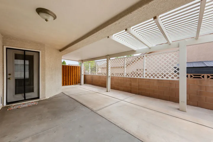 Covered patio featuring concrete flooring, a lattice privacy screen, and a partial wood fence