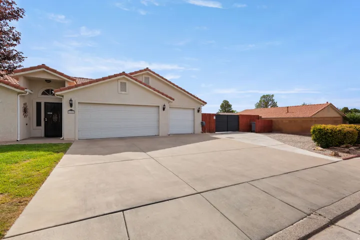 Stucco exterior with a tiled roof, multi-car concrete driveway, and a secure side gate
