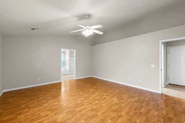 Spacious interior featuring wood-finish flooring, vaulted ceiling, and a ceiling fan