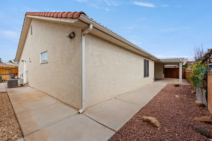 Stucco exterior with a terracotta tile roof, leading to a covered patio  and a gravel landscaping area