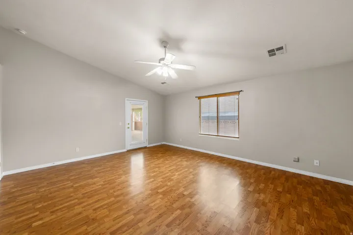 Vaulted ceilings with a ceiling fan, wood-finish flooring, and a glass-paned door