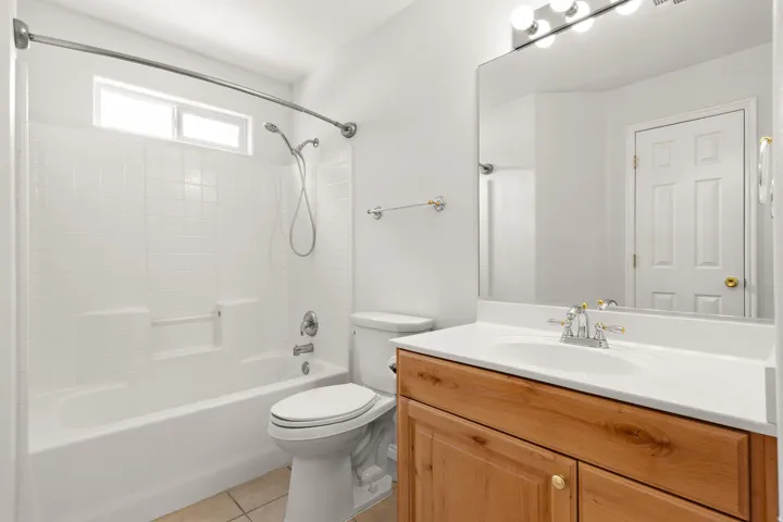 White tiled shower and tub combination with a transom window
