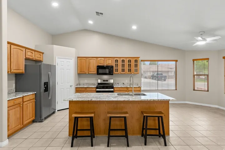 Kitchen featuring a central island, wood cabinetry, granite countertops, and tile flooring