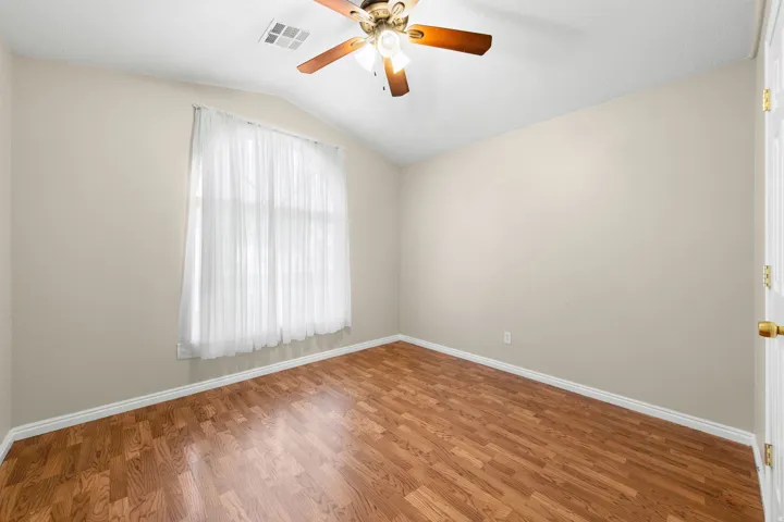 Angled ceiling featuring a ceiling fan, recessed window, wood-finish flooring, and light-toned walls