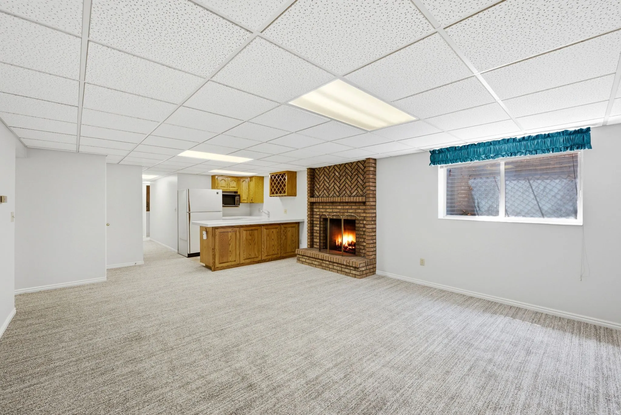 Brick fireplace, wood-finish cabinetry, built-in counter space, integrated appliances, and wall-to-wall carpeting