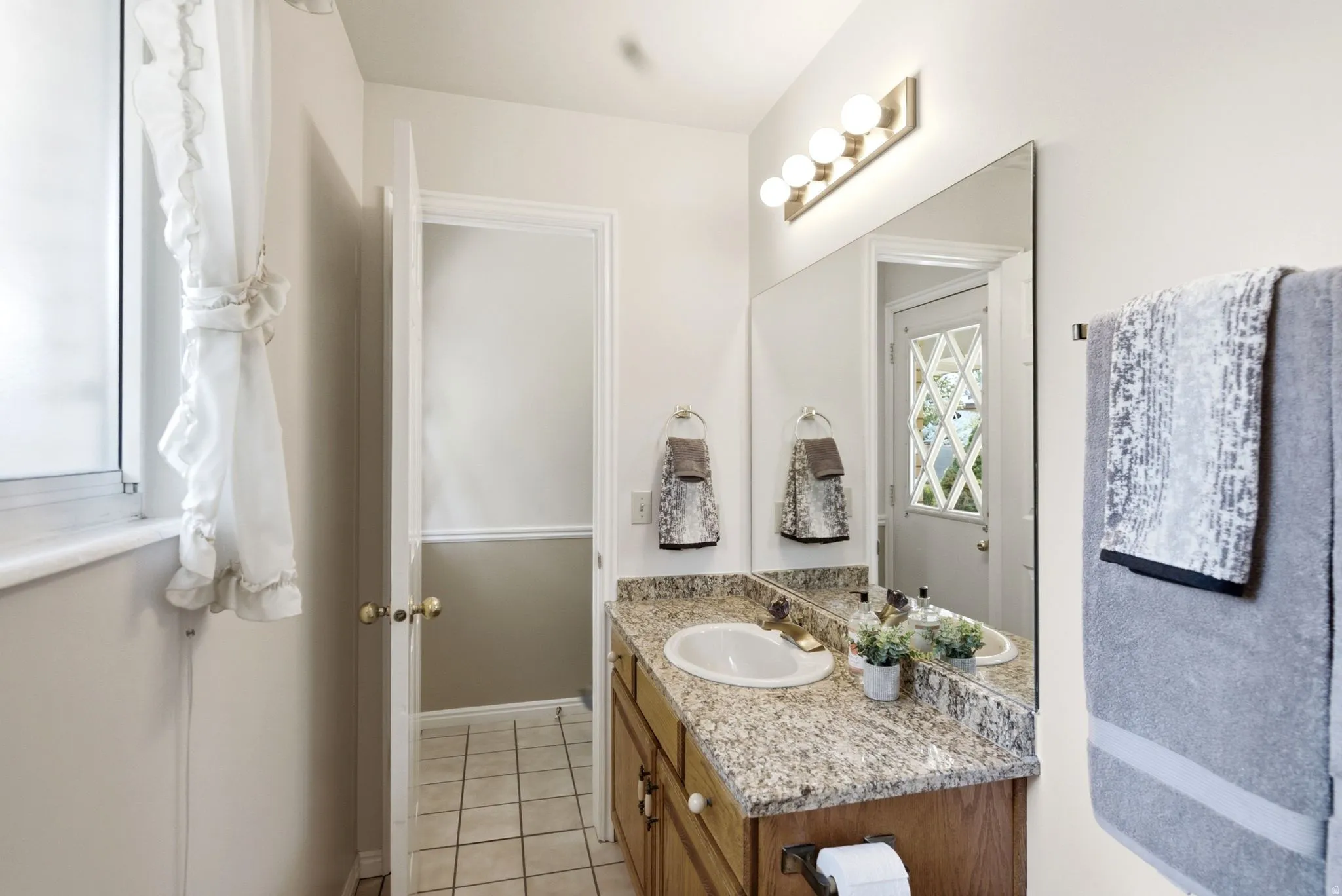 Bathroom vanity featuring a granite-style countertop, undermount sink, and wood-finish cabinetry