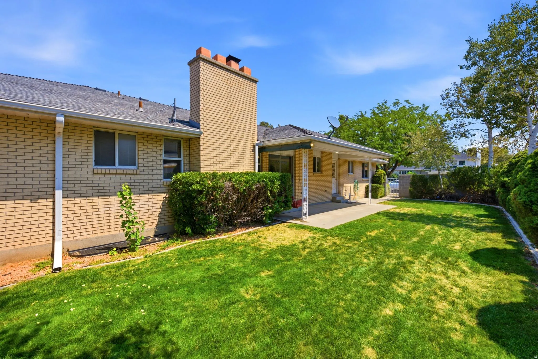 Expansive grassy yard with mature trees and a covered patio area